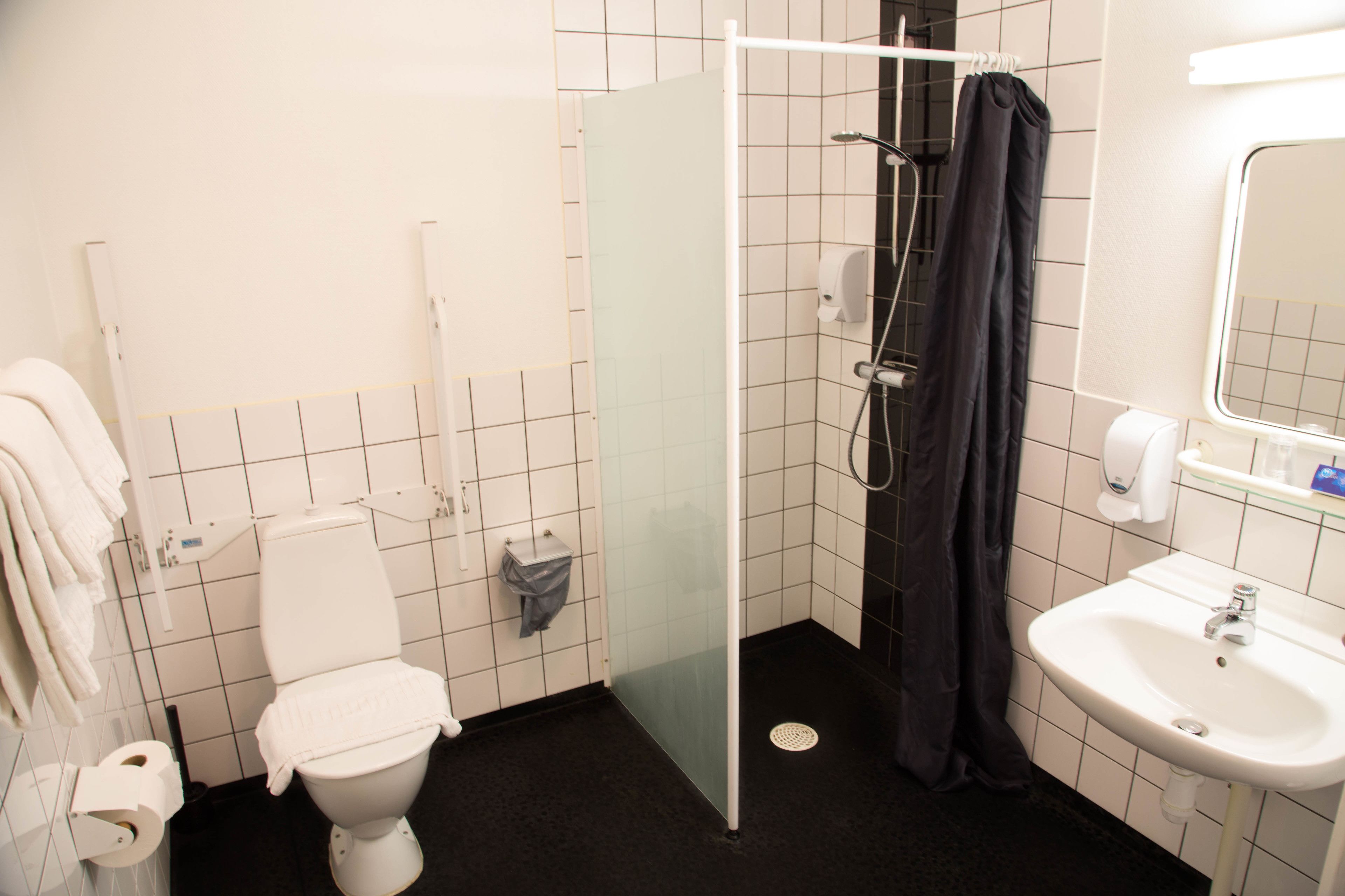 Une salle de bain comprenant des toilettes, une douche fermée par une paroi de verre et un lavabo.