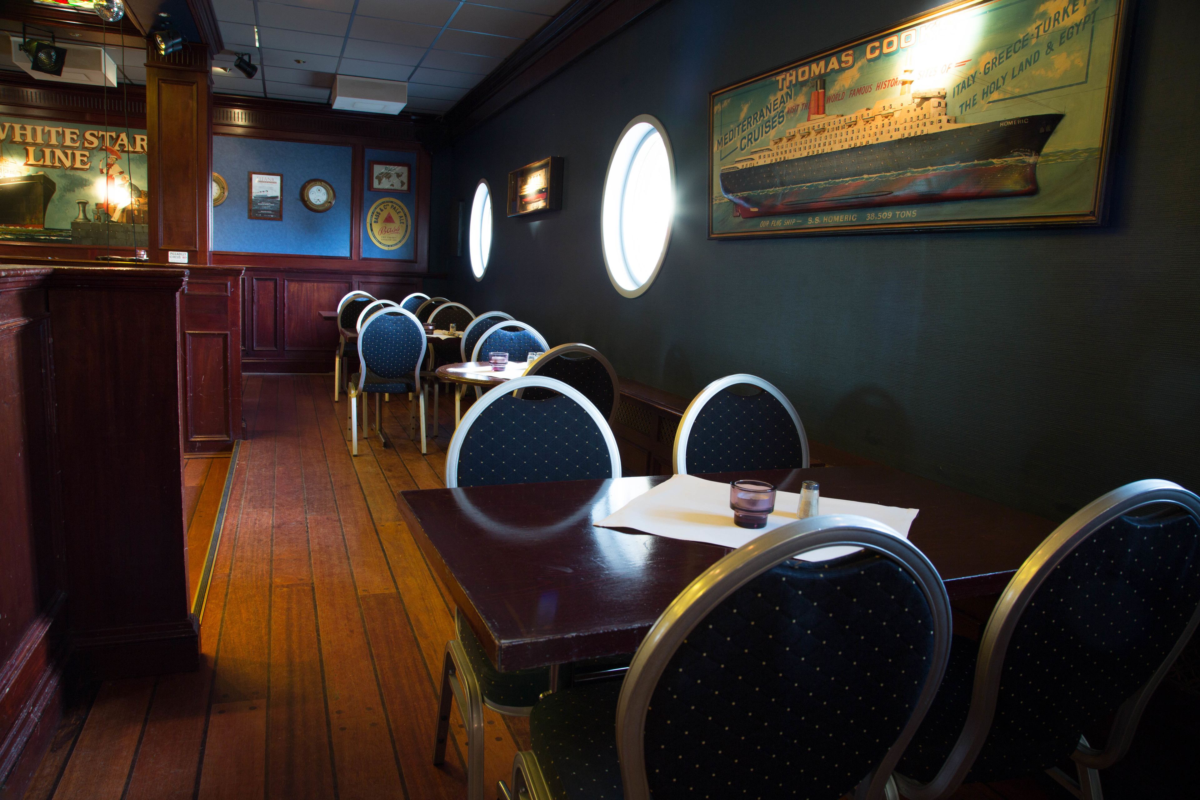 A restaurant interior with wooden floors, round tables, and blue chairs.