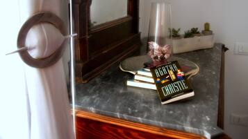 Una stanza con una scrivania in legno, uno specchio, un vaso con fiori e un libro intitolato