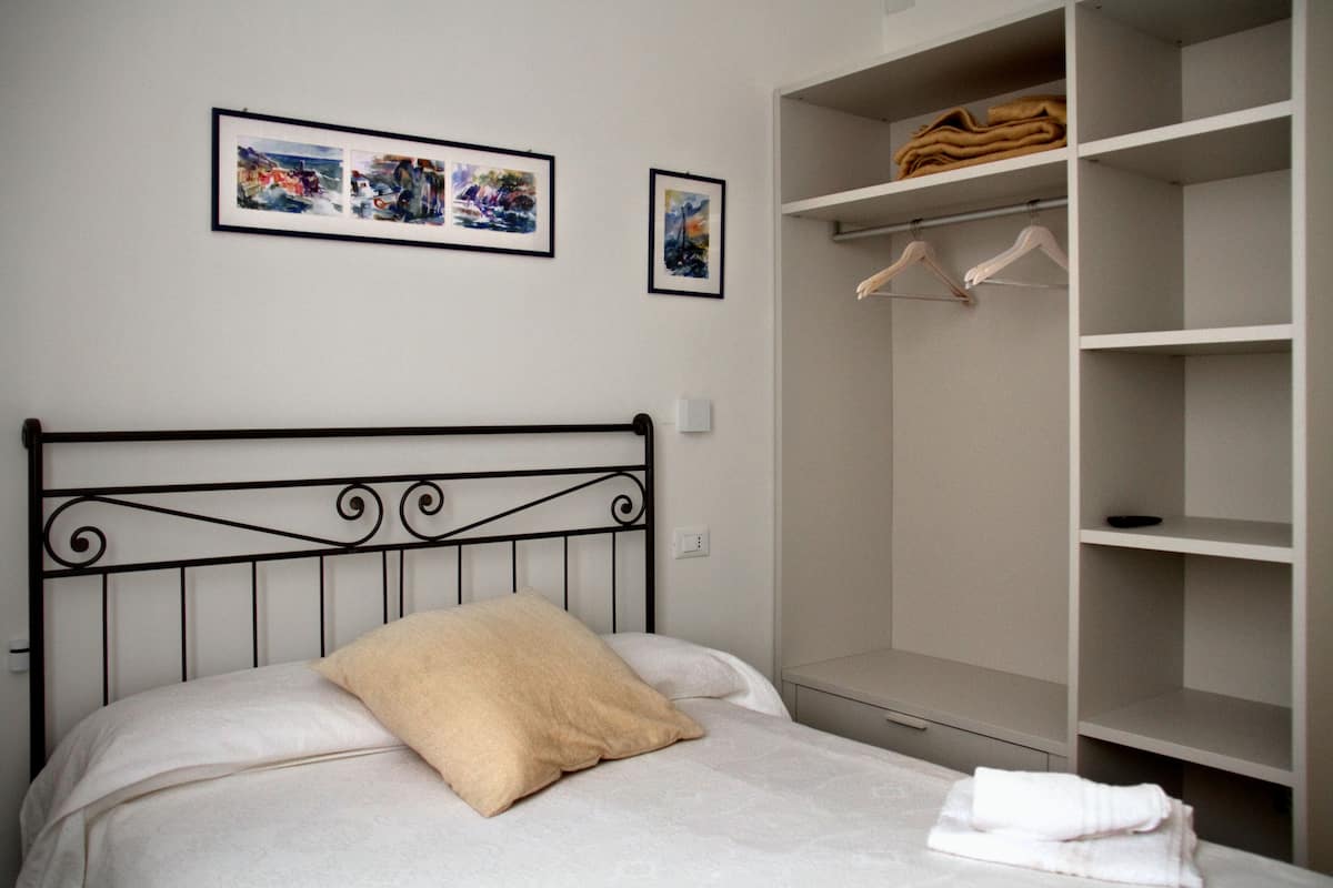 A bedroom with a bed, a wardrobe, and two framed pictures on the wall.
