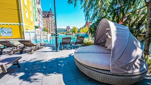 A poolside seating area with a round wicker chair, lounge chairs, and a pool. - Europa-Park Erlebnis-Resort, Hotel Krønasår (Rust)