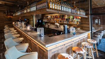 Eine Bar mit Holzausstattung, Barhocker und einer Auswahl an Spirituosenflaschen.