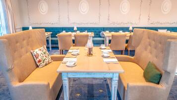 A dining area with a long table set for four, surrounded by cushioned seating.