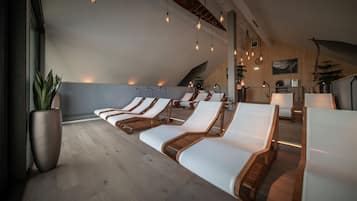 Relax in a serene space with lounge chairs, a potted plant, and pendant lights.