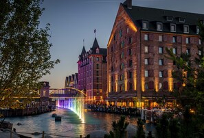 Un hotel junto al río con un edificio destacado que cuenta con una torre y numerosas ventanas.