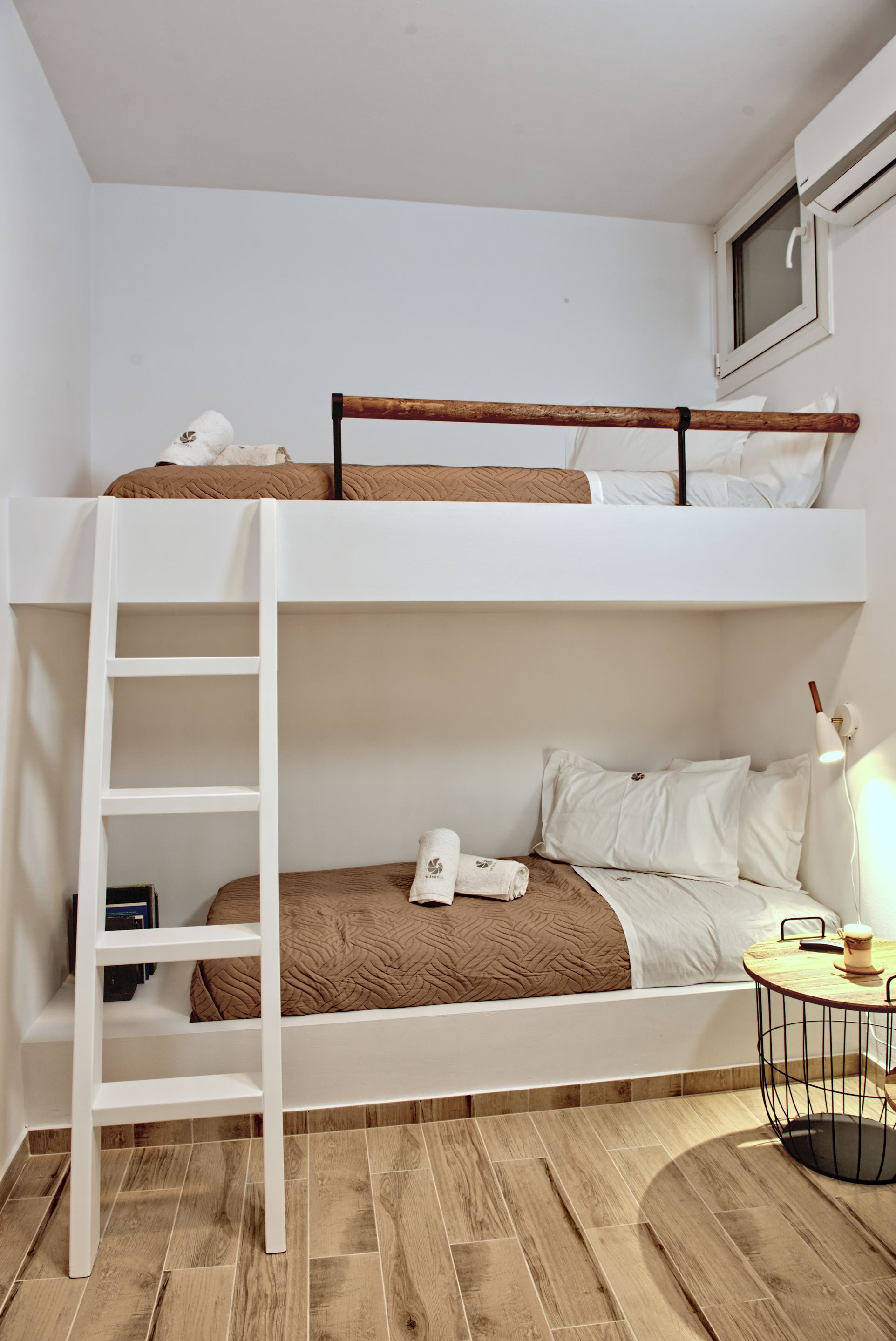 A bunk bed with a ladder, a bedside table with a lamp, and a small shelf.