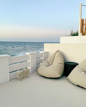 A balcony with a view of the sea, featuring white railings, beige cushions, and wicker furniture. - Seashell Suite by the Sea (Hersonissos)