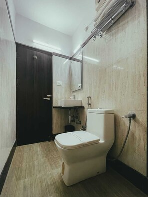 A compact bathroom with a toilet, sink, and mirror.