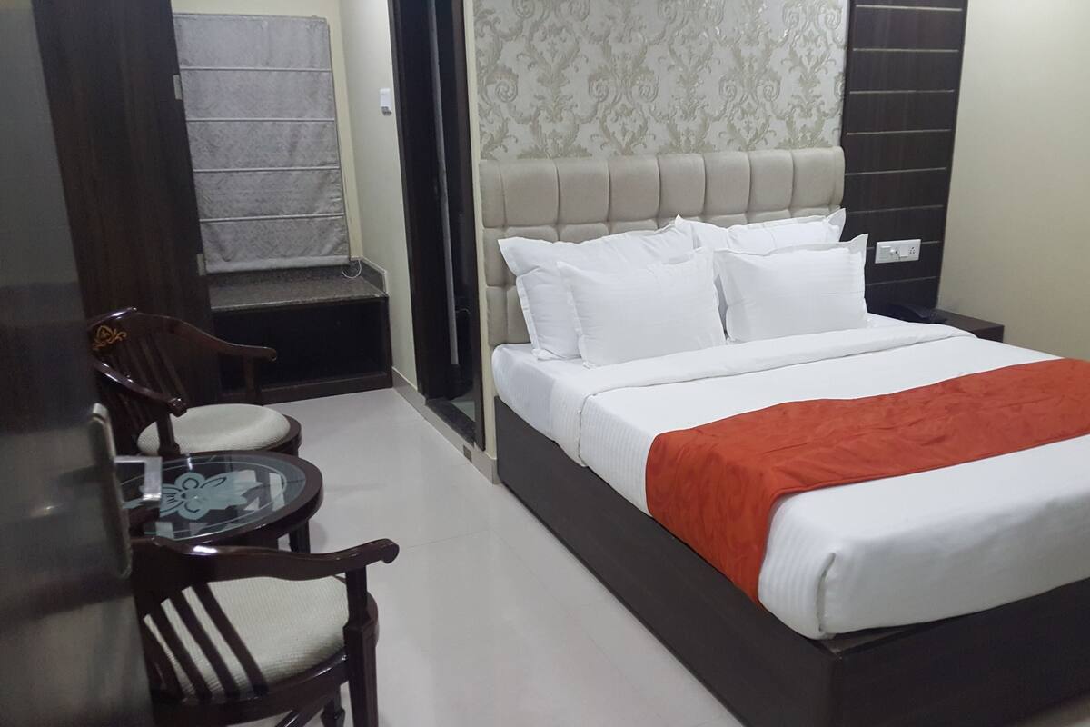 Habitació d'hotel amb un llit, una cadira, una taula petita i una porta.