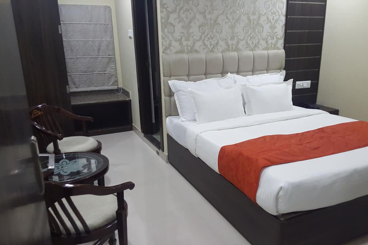 Habitació d'hotel amb un llit, una cadira, una taula petita i un armari.