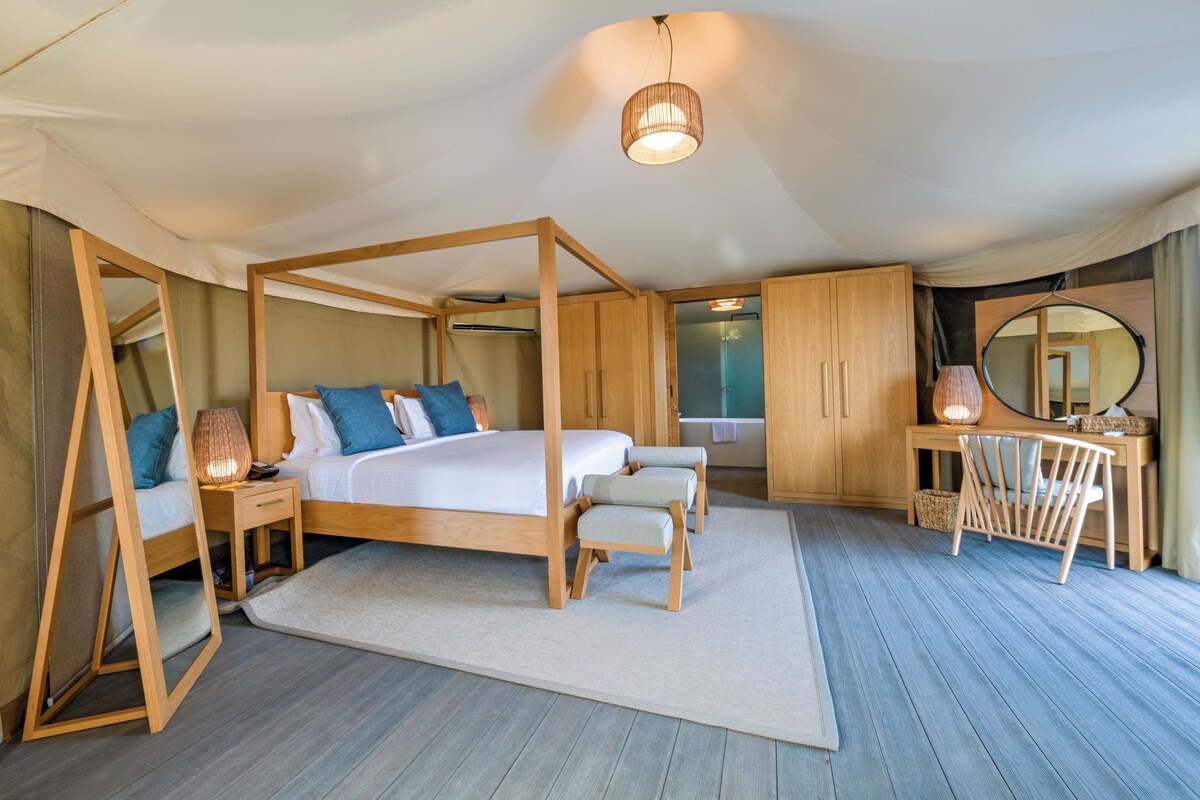 Un dormitorio amplio con cama con dosel, muebles de madera y un espejo grande.