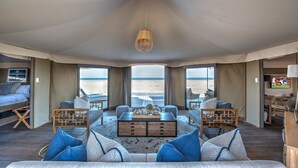A spacious living area with a large window overlooking the beach, a wooden coffee table, and comfortable seating.