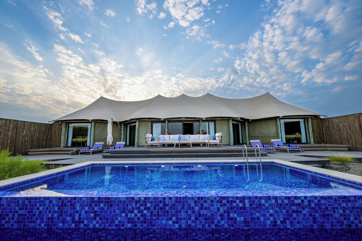 A swimming pool with lounge chairs and a covered seating area.