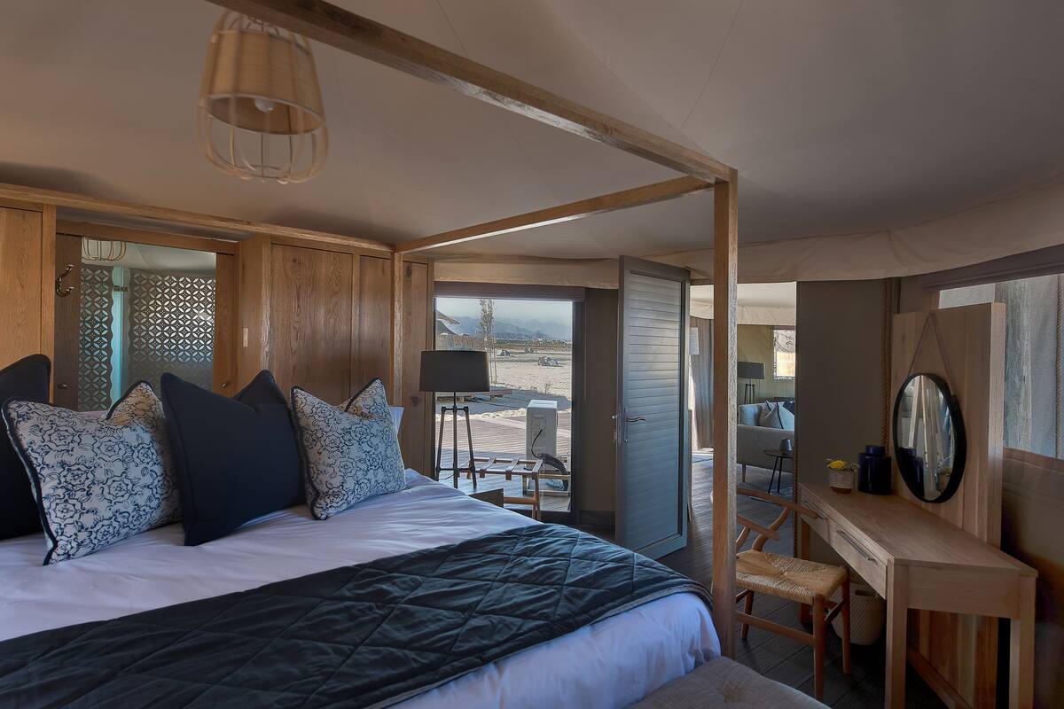 A bedroom with a large bed, a desk, and a view of the outdoors.