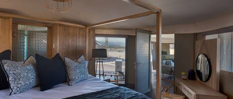 A bedroom with a large bed, a desk, and a view of the outdoors.