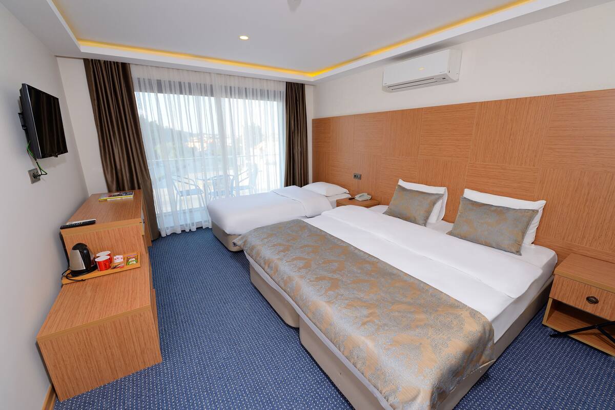 Habitación de hotel con dos camas, un escritorio con teléfono, televisión y aire acondicionado.