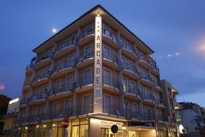 Een meerlaags hotel met balkons en een opvallend verticaal bord waarop 