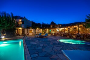 A pool area with lounge chairs and a bar area with outdoor seating. - Villa Sofia (Andros)