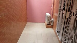 A narrow hallway with tiled flooring, a pink door, and a radiator on the right.