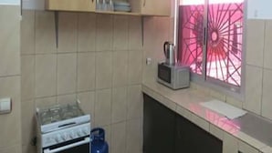 A kitchen with a gas stove, a microwave, and a gas cylinder.