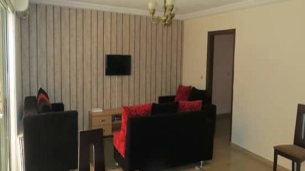A living room with a sofa, a TV, and a dining table.