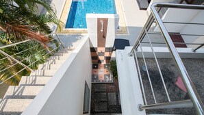 A staircase leading to a pool area with a tiled wall and palm trees. - Lemon House (Rawai)