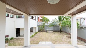 A covered courtyard with a concrete fountain, palm trees, and a view of neighboring buildings. - Lemon House (Rawai)