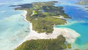 An aerial view of a tropical island with clear turquoise waters, sandy beaches, and lush greenery. - Villa Banian (Trou d'Eau Douce)