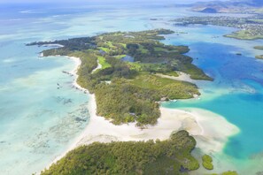 Vista aerea di un'isola tropicale con acque cristalline turchesi, spiagge sabbiose e vegetazione lussureggiante.