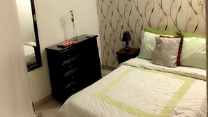 A bedroom with a bed, dresser, nightstand, and a mirror. - Résidence Bimbois (Abidjan)