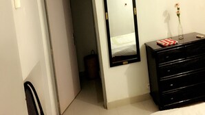 A hotel room with a bed, a dresser, a mirror, and an air conditioning unit. - Résidence Bimbois (Abidjan)