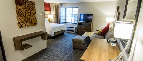 Une chambre d’hôtel avec un lit, un bureau, une télévision et une grande fenêtre.