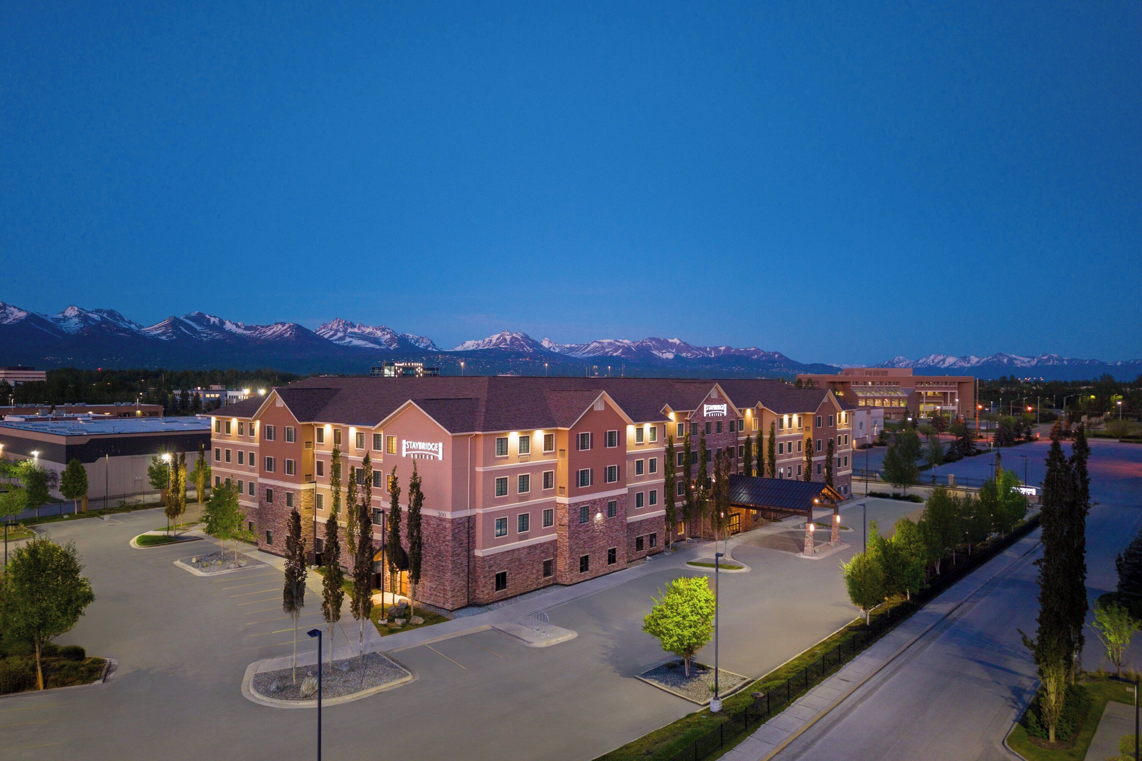A hotel with a stone facade, multiple floors, and a parking lot in front.