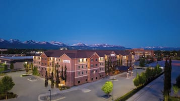 A hotel with a stone facade, multiple floors, and a parking lot in front.