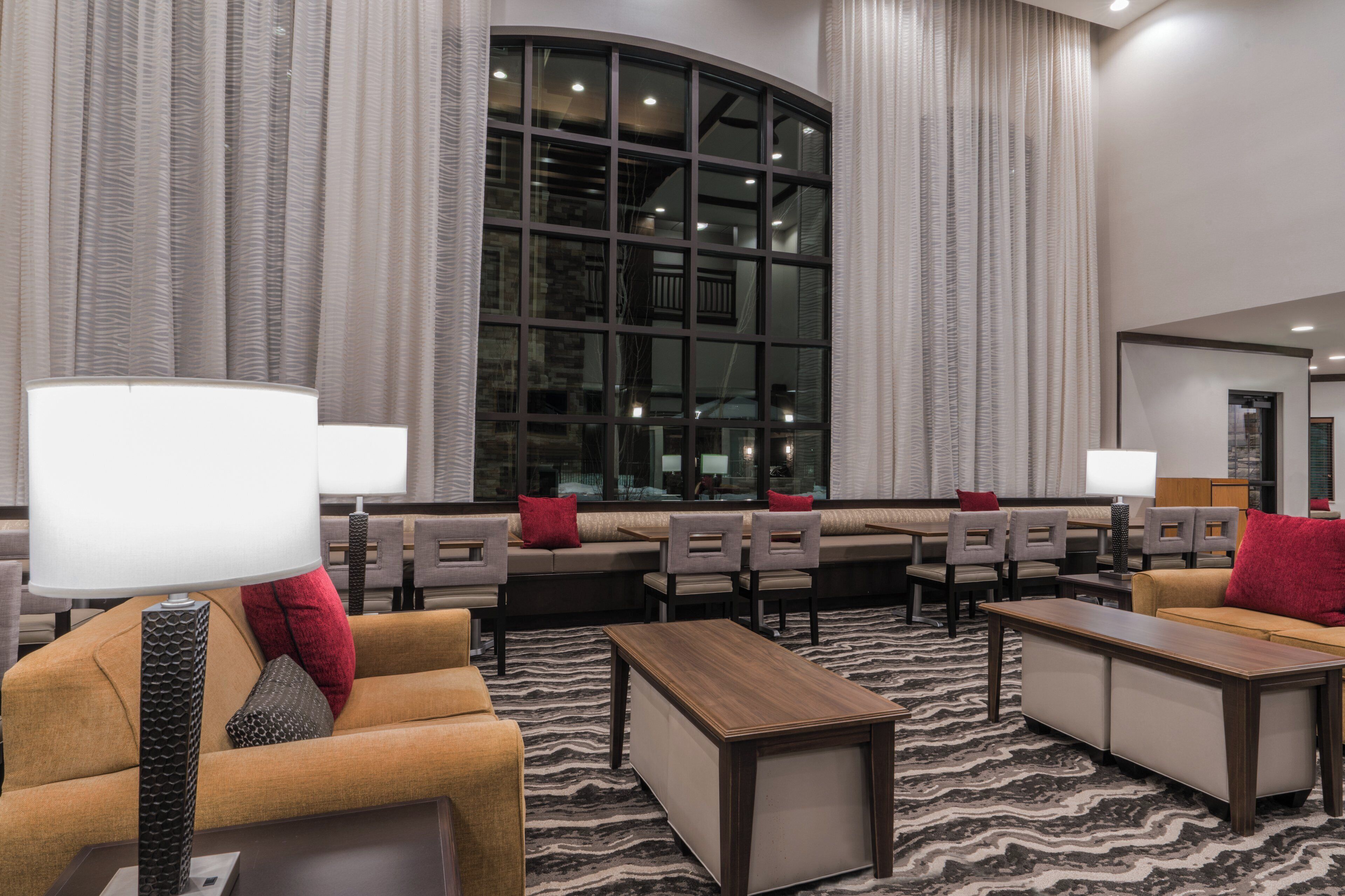 A hotel lobby with seating areas, a large window, and a patterned carpet.