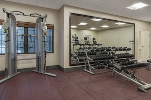 Une salle de sport équipée de matériel d’exercice, notamment un support à squats, des haltères et des tapis de course.