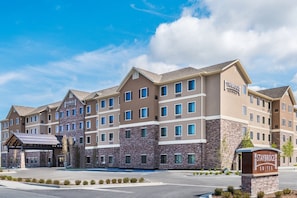 Un hôtel Staybridge Suites doté d’une façade en pierre, de plusieurs étages et d’une entrée abritée.