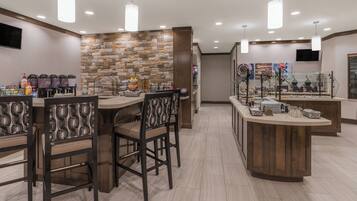 A modern breakfast bar with seating, a stone accent wall, and various breakfast items.