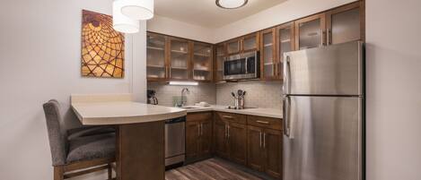 A modern kitchen with wooden cabinets, stainless steel appliances, and a bar area.