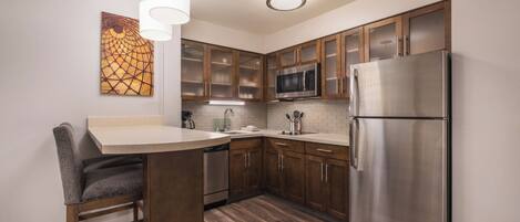Una cocina moderna con armarios de madera, electrodomésticos de acero inoxidable y un taburete de bar.