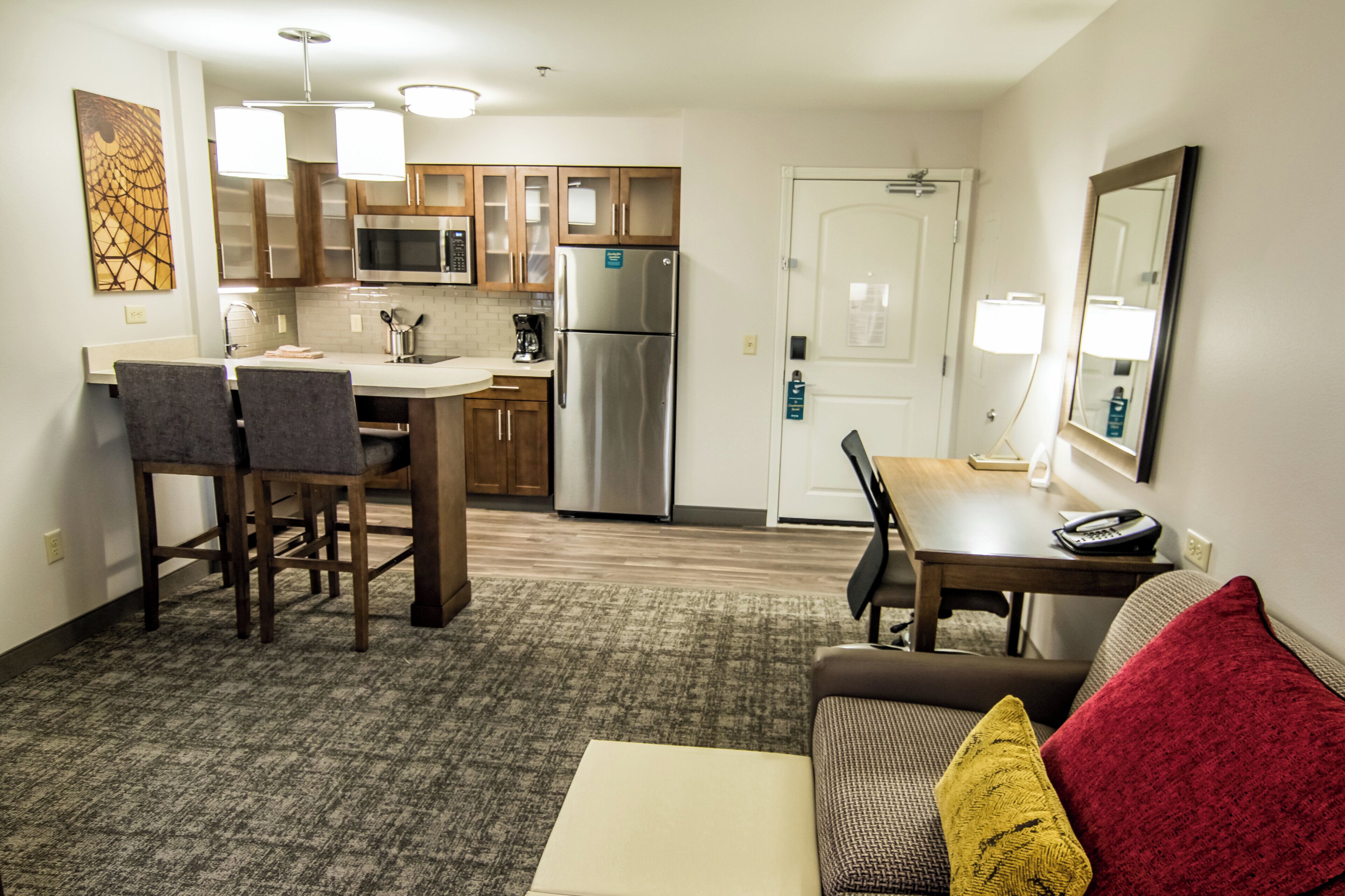 A compact hotel room with a kitchenette, a dining area, and a living space with a sofa and a coffee table.