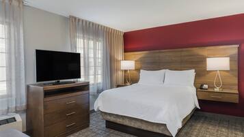 Una habitación de hotel con una cama, televisión, cómoda y mesita de noche con lámparas.