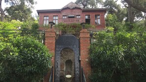 A traditional wooden house with a brick entrance gate, surrounded by lush greenery. - Kosk Orman Butik Otel (Adalar)