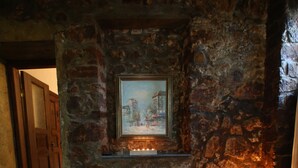 A bed with white linens in a room with stone walls and a painting above it. - Kosk Orman Butik Otel (Adalar)