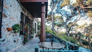 A stone building with a wooden deck, potted plants, and outdoor seating. - Kosk Orman Butik Otel (Adalar)