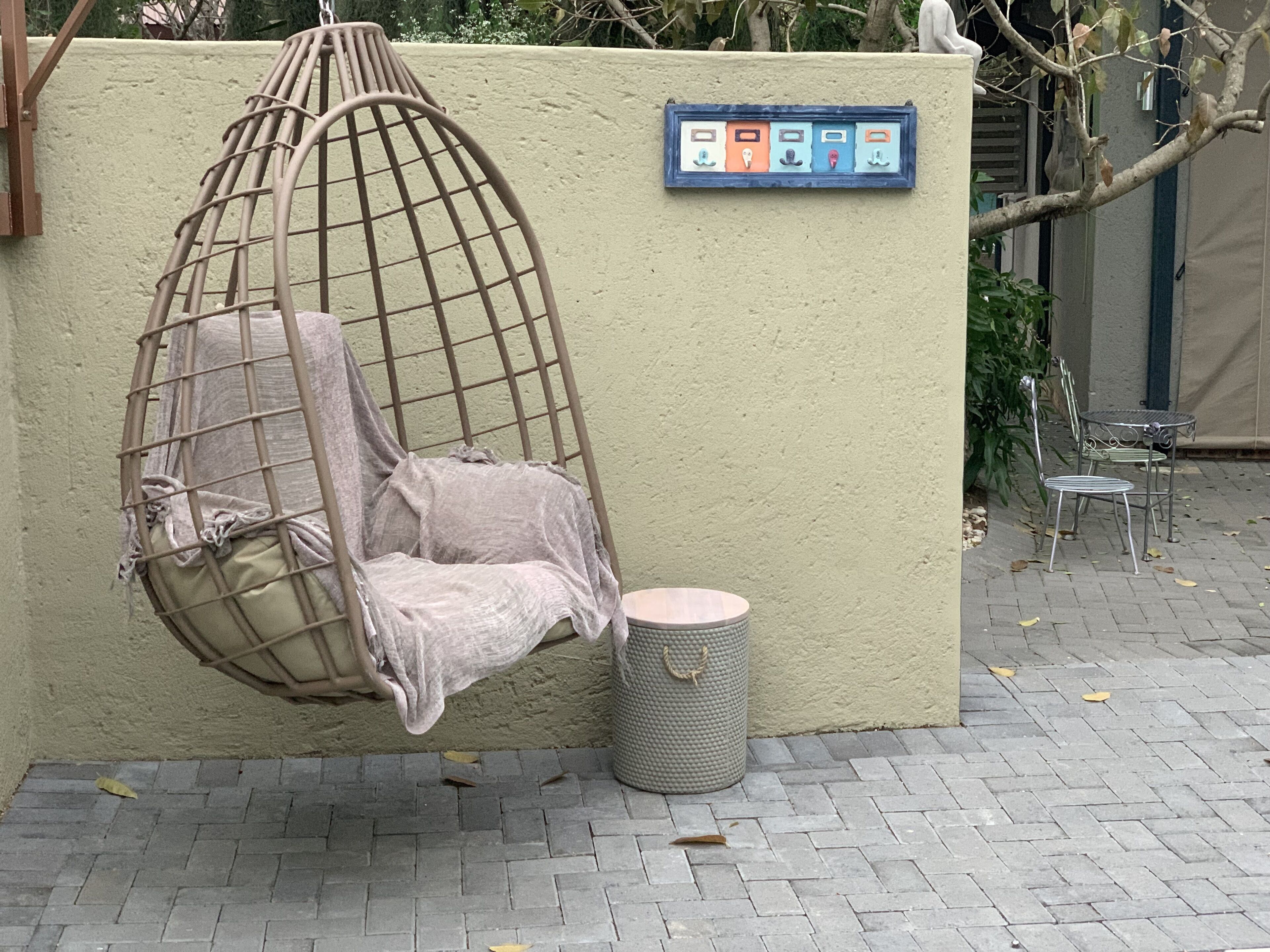 Un fauteuil suspendu avec un coussin, une poubelle et une boîte aux lettres fixée au mur.