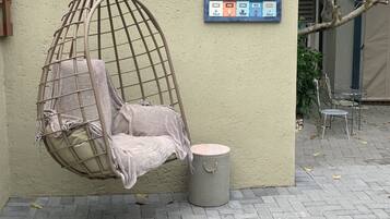 Un fauteuil suspendu avec un coussin, une poubelle et une boîte aux lettres fixée au mur.