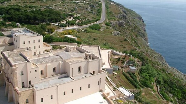 Un ensemble de bâtiments situé sur la côte, composé de plusieurs structures, avec une route sinueuse et une vue sur la mer.