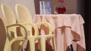 Une table recouverte d’une nappe blanche, deux chaises, un menu et une carafe.
