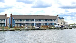 Et hotel ved vandet med flere balkoner og en bro med både.